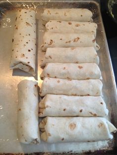 several burritos are lined up on a baking sheet and ready to go into the oven