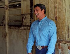 a man in blue shirt and jeans standing next to an old building