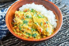 a wooden bowl filled with rice and chicken curry