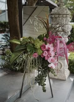 a vase with flowers and greenery is on display in front of a sign that says vrrn