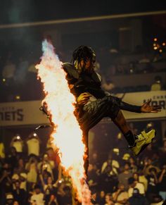 a man is doing tricks on fire while people watch from the stands in the background