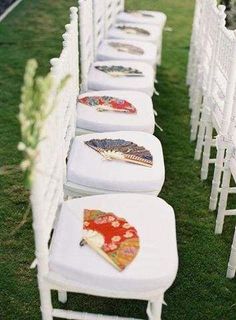 rows of white chairs with embroidered umbrellas on them