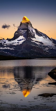 a mountain is shown with the reflection of it's peak in the still water