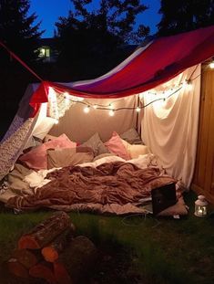 a bed in the middle of a yard with lights strung from it's sides