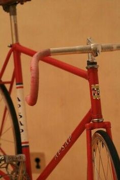 a red bicycle is parked in front of a wall