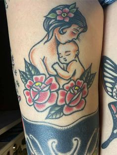 a woman holding a baby in her arms with flowers on the side of her leg