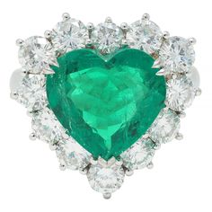 Centering a heart cut emerald weighing 4.62 carats - transparent medium green in color Natural Colombian in origin with minor modern clarity enhancement  Set with split talon prongs with a round brilliant cut diamond halo surround  Weighing approximately 2.38 carats total - G color with VS2 clarity Prong set with a pierced scroll motif gallery Inscribed with carat weight Stamped for 18 karat gold With maker's mark Circa: 2000s Ring size: 6 and sizable Measures north to south 28.0 mm and sits 8.0 Heart Halo Ring, Heart Halo, Glitter Bag, Green Rings, Modern Engagement Rings, Magical Jewelry, Colombian Emeralds, Modern Ring, Maker's Mark