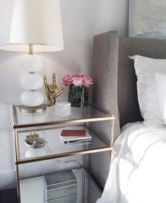 a bedroom with a bed, nightstand and flowers on the night stand next to it