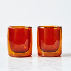 two orange glass cups sitting on top of a white counter