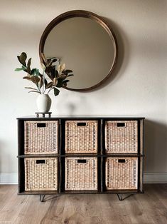 four wicker baskets sit in front of a round mirror on the wall next to a dresser