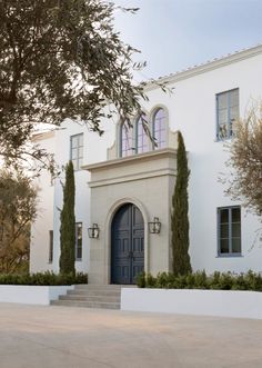 a large white house with trees and bushes around it