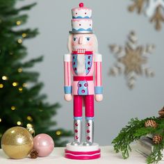 a nutcracker figurine sitting on top of a table next to a christmas tree