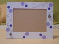 a white frame with purple polka dots and two little butterflies on it sitting on a bed