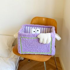 a stuffed animal in a purple blanket on top of a wooden chair