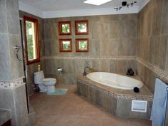 a bathroom that has a large tub in the middle of it and windows on the wall