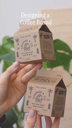 two boxes with designs on them are being held by someone's hands in front of a plant