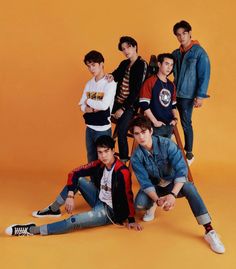 the group of young men are posing together for a photo in front of an orange background