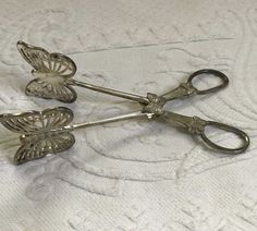 two silver scissors sitting on top of a white sheet