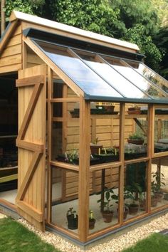 a small wooden greenhouse with lots of plants growing inside it and windows on the side