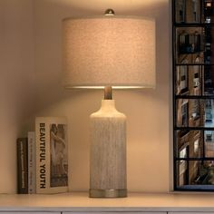 a lamp sitting on top of a white table next to a book shelf and window