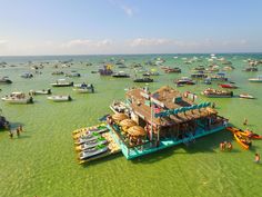 a group of boats floating in the ocean next to a dock with people on it