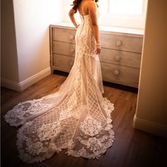 a woman standing in front of a window wearing a wedding dress with lace on it