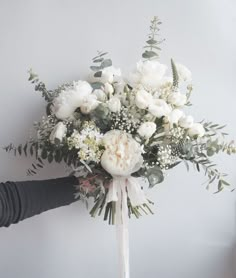 a bouquet of white flowers is being held by someone's arm and the other hand