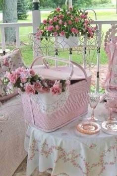 a pink and white basket sitting on top of a table next to a chair covered in flowers