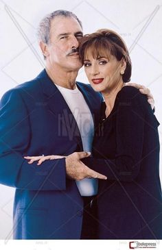 an older man and woman posing for a photo with their arms around each other in front of a white background