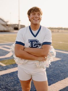 a male football player is standing on the field with his arms crossed and looking at the camera