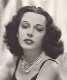 an old black and white photo of a woman wearing pearls