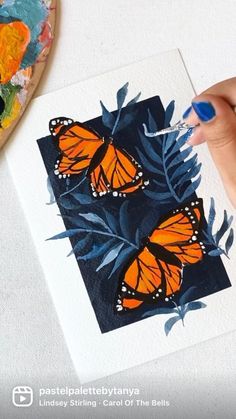 a person is holding a paintbrush in their hand and painting butterflies on a piece of paper