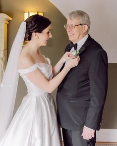 an older man helping his bride put on her wedding dress