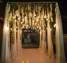 an outdoor wedding ceremony with white drapes and greenery draped over the entrance to the venue