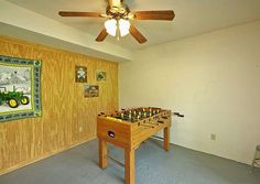 a room with a foosball table in it and a fan hanging from the ceiling