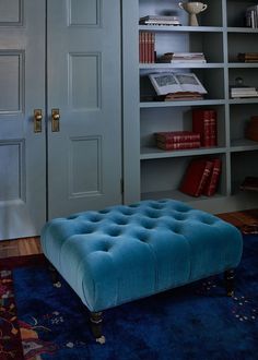 a blue ottoman sitting in front of a book shelf