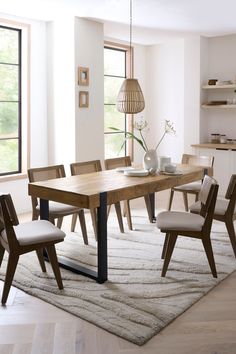 a dining room table with chairs and a rug on the floor in front of it