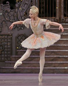 a ballerina in a tutu and dress is doing a ballet move on the stage