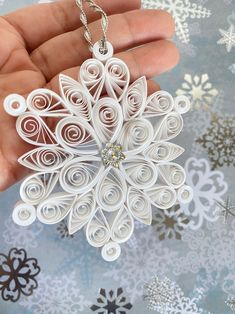 a hand holding a white origami snowflake