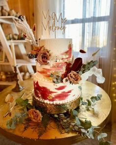 a wedding cake with flowers and feathers on top