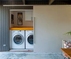 a washer and dryer in a room next to a table with a potted plant