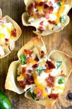 small shells filled with bacon and cheese on top of a wooden table next to a green pepper