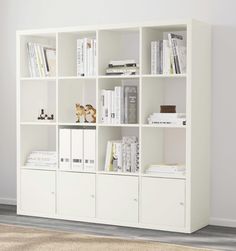 a white bookcase filled with lots of books on top of a carpeted floor