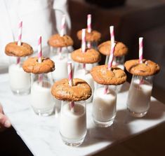 there are many cookies and milks on the tray with straws in each one