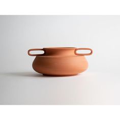 a clay pot with two handles sitting on a white surface