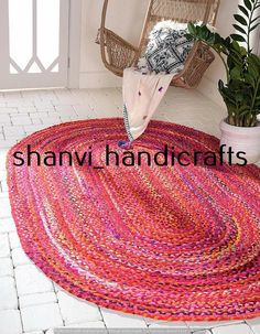 a pink rug on the floor next to a chair and potted plant