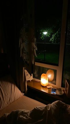 a bed in a dark room next to a window with a lit candle on it