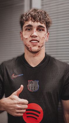 a man with blood all over his face holding a red frisbee and giving the thumbs up sign