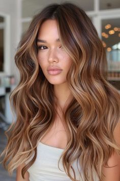 Woman with long, wavy hair and natural makeup, standing indoors. Brown Blonde Caramel Hair, Hair Colour Caramel Brown, Long Caramel Balayage, Copper Hair Honey Highlights, Bronde Balayage With Copper Tones, Light Chocolate Brown Hair Highlights, Caramel Brown Blonde Highlights, Honey Highlights On Auburn Hair, Dimensional Brunette Caramel