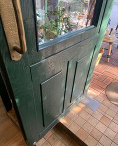 a green door with glass on the side and brick flooring in front of it